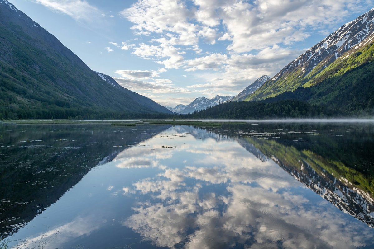 Green mountains beside a lake under a blue sky on the Kenai Peninsula