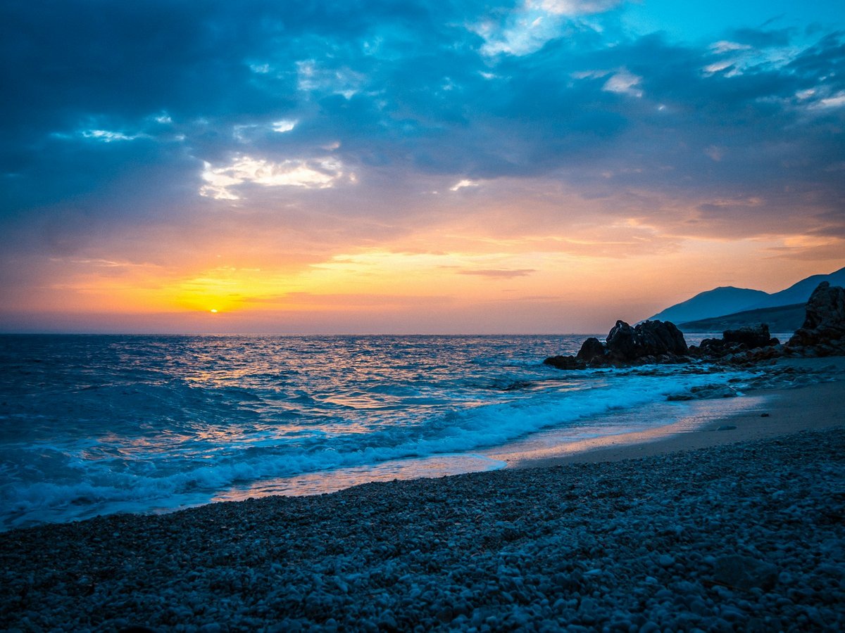 Rocky shoreline and turquoise water at Himarë on the Albanian Riviera, with mountains behind