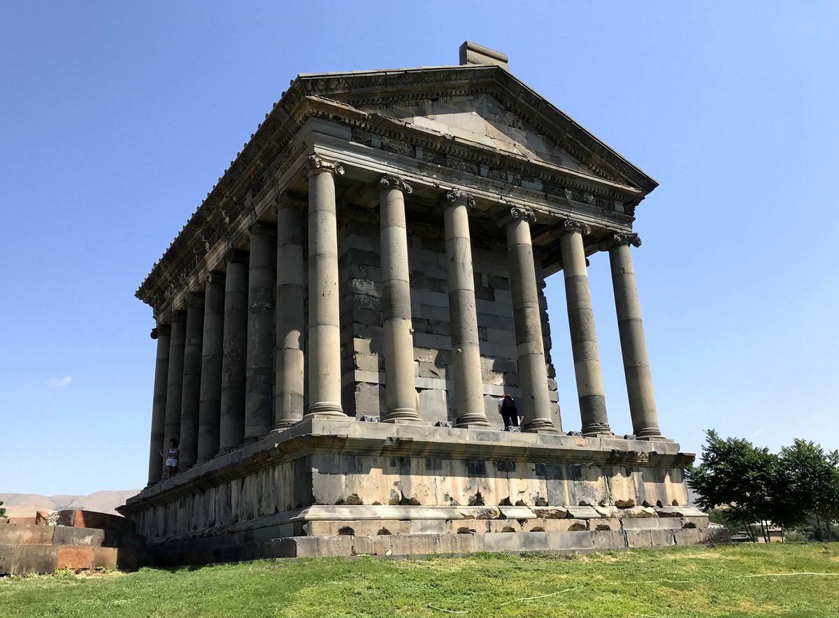 The colonnaded Greco-Roman Temple of Garni standing on a grassy platform under a clear sky