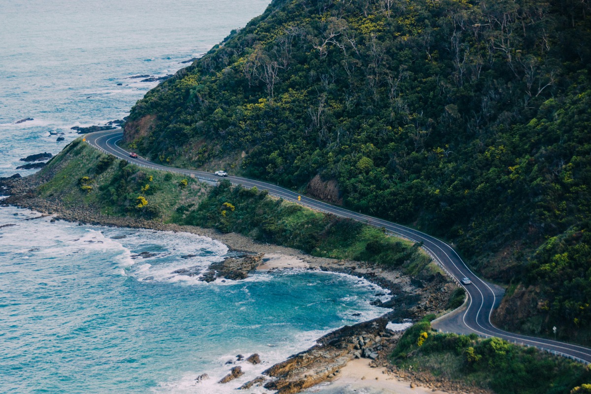 Great Ocean Road curving beside cliffs and dense coastal forest