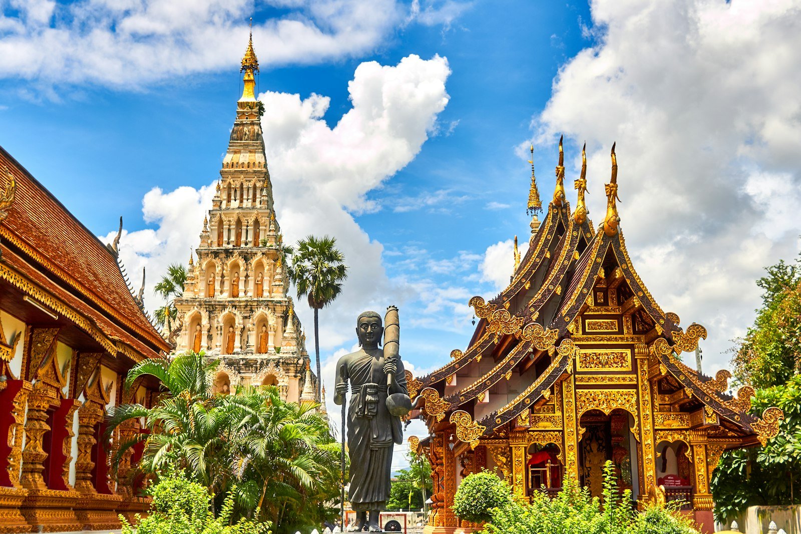 Ornate temple statues and buildings under a blue sky in Thailand