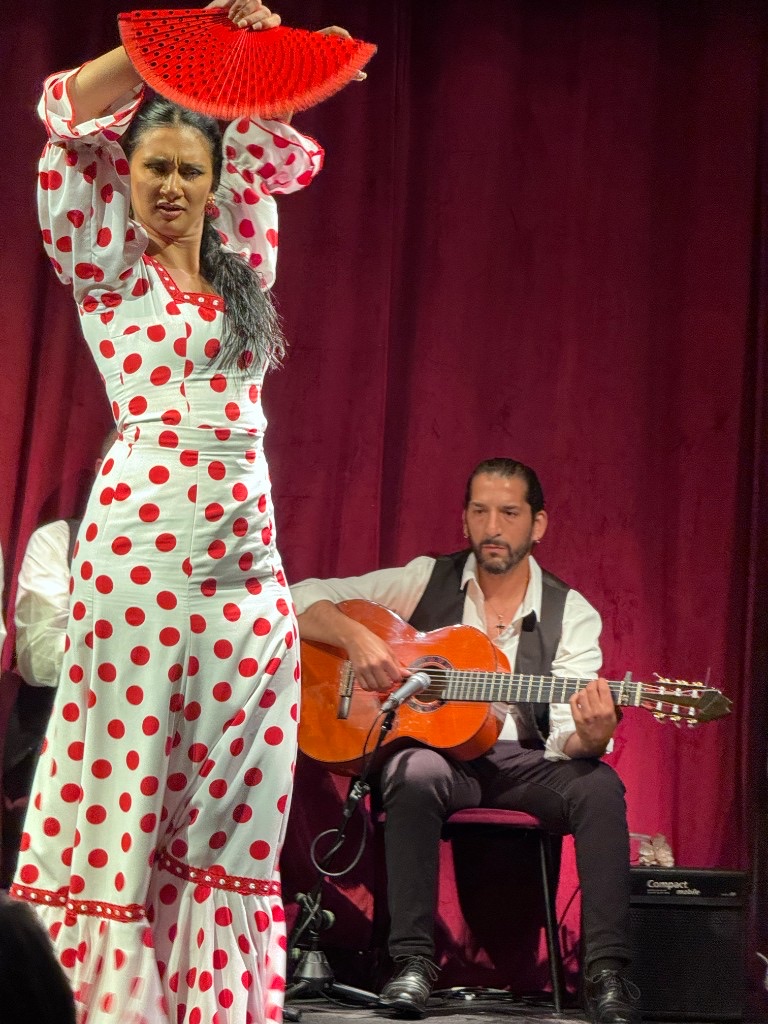 Flamenco dancer with red fan and guitarist performing at Casa Sors tablao in Barcelona