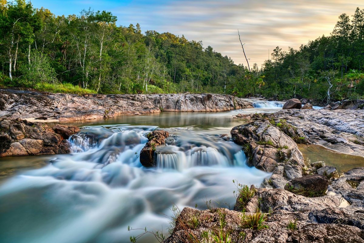 A river flowing through lush rainforest in Mountain Pine Ridge, Belize, with rocky pools, small waterfalls and dense vegetation