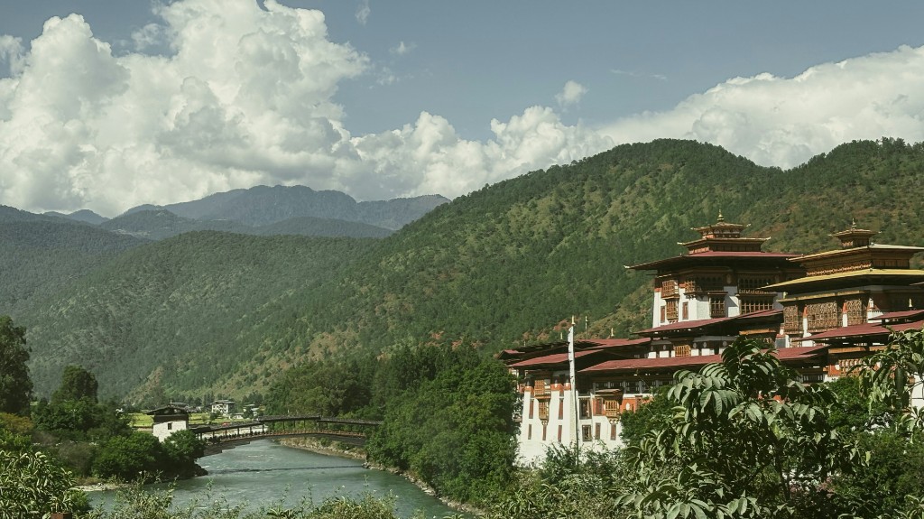 Punakha Dzong beside the river with forested Himalayan mountains beyond