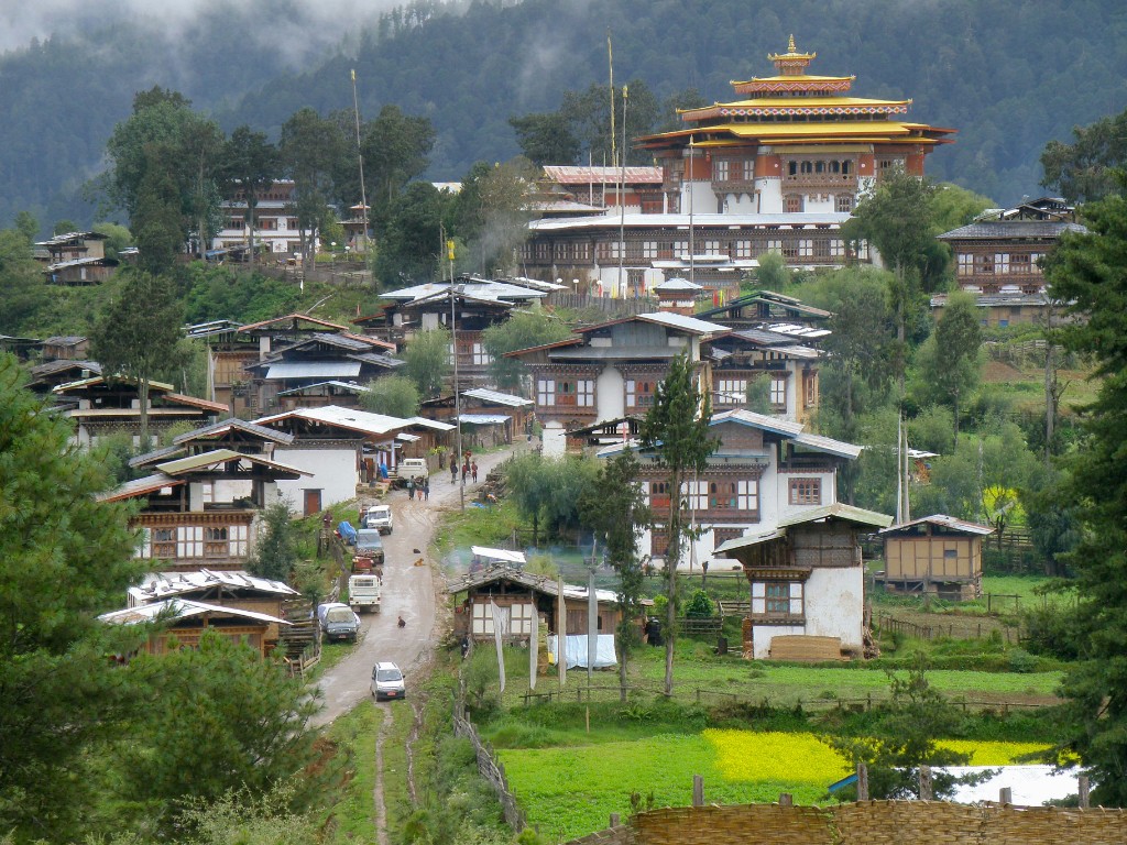 Village and monastery on a hillside in Phobjikha Valley, Bhutan, under misty mountains