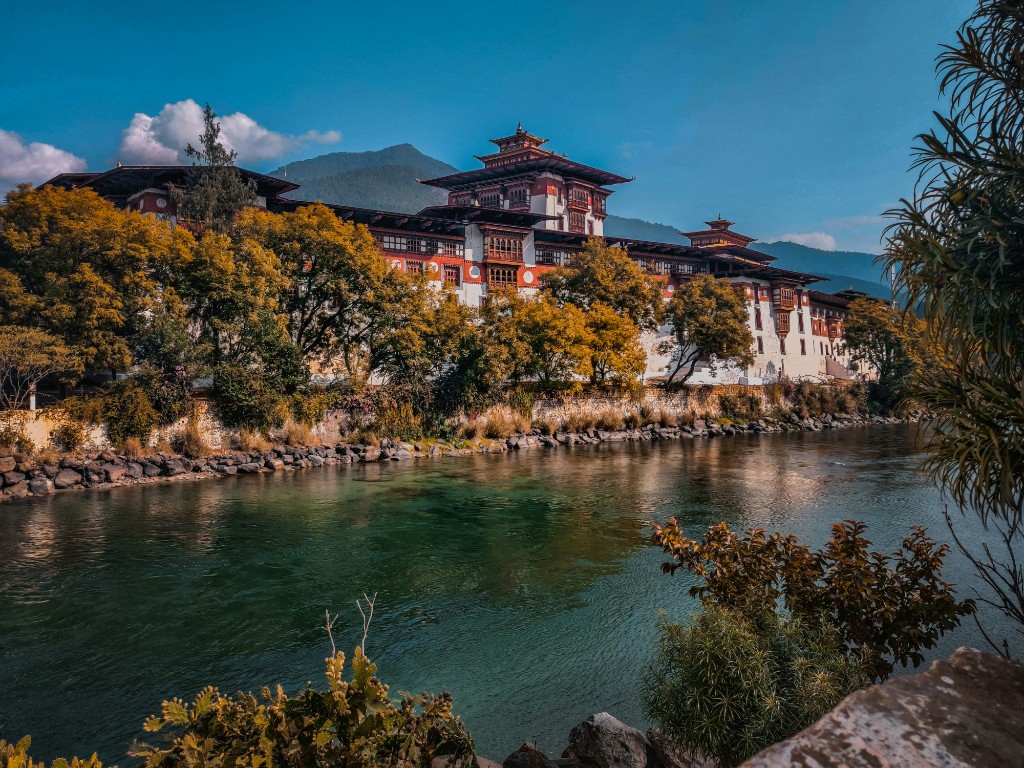 Punakha Dzong along a green river with forested mountains beyond