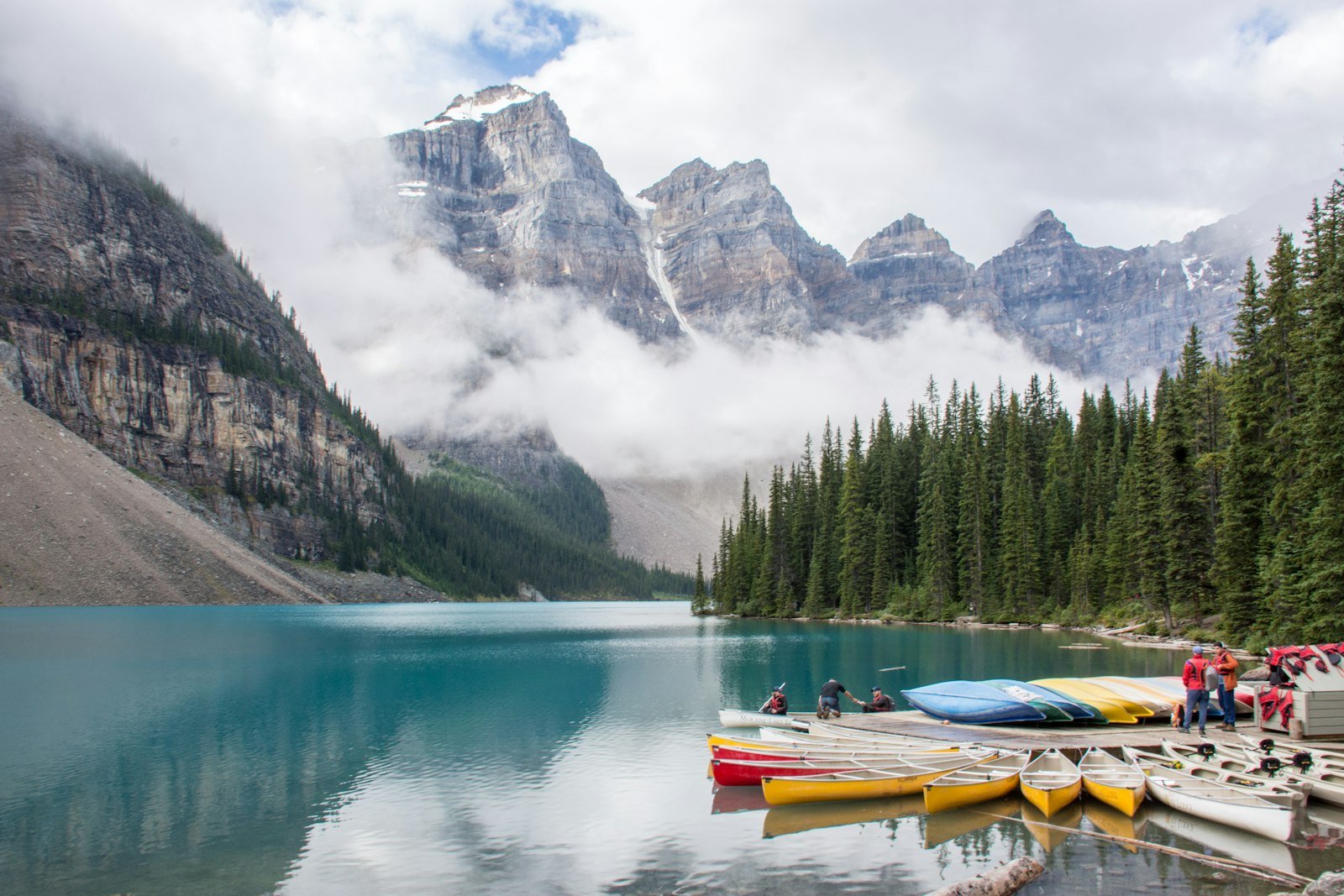 Pine trees and icy mountains beside a lake along the Icefields Parkway