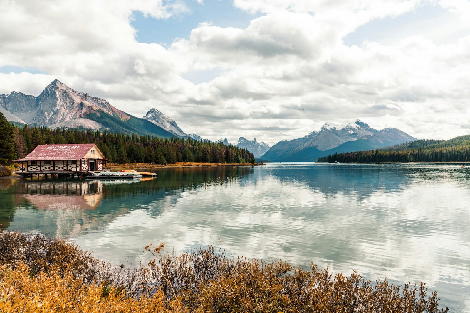Pyramid Lake with a boathouse and mountains reflected in calm water near Jasper