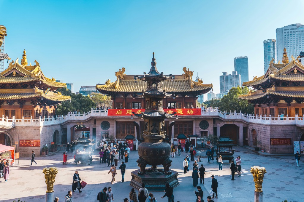 Jing’an Temple courtyard with a bronze incense burner, golden-tiled roofs, and Shanghai skyscrapers beyond