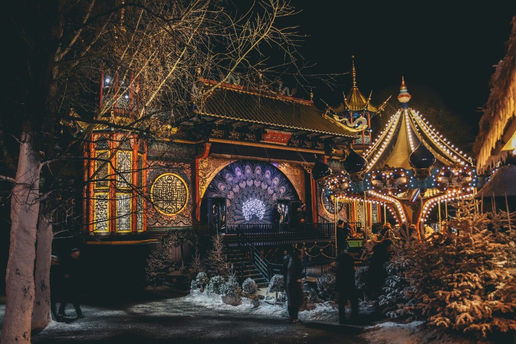 Illuminated carousel and pagoda-style pavilion at Tivoli Gardens in Copenhagen at night