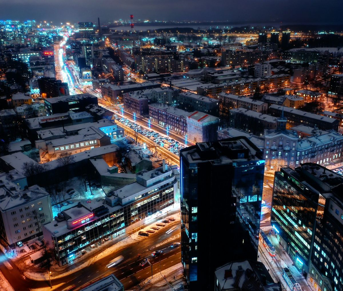 Vista aérea nocturna de calles nevadas en Tallin, semáforos y edificios modernos