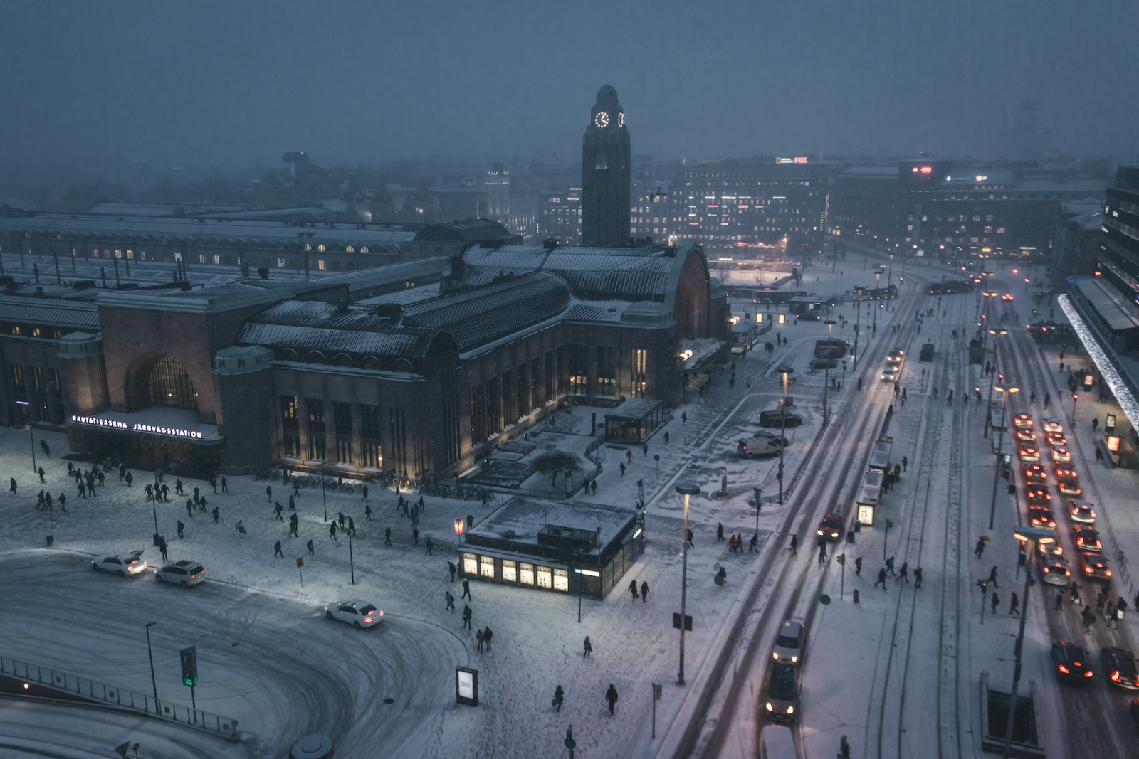 Helsinki Central Railway Station and snow-covered streets at winter dusk with illuminated buildings and trams
