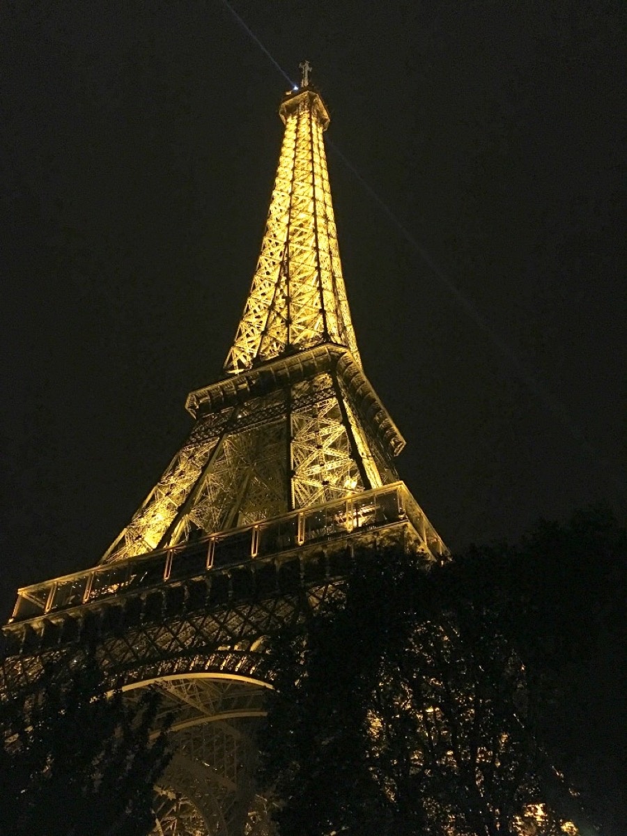 The Eiffel Tower illuminated at night from the base, glowing gold against a dark Paris sky
