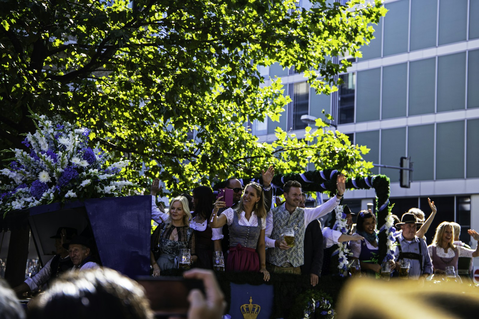 Men and women in traditional Bavarian dirndl and lederhosen celebrating during a festive parade