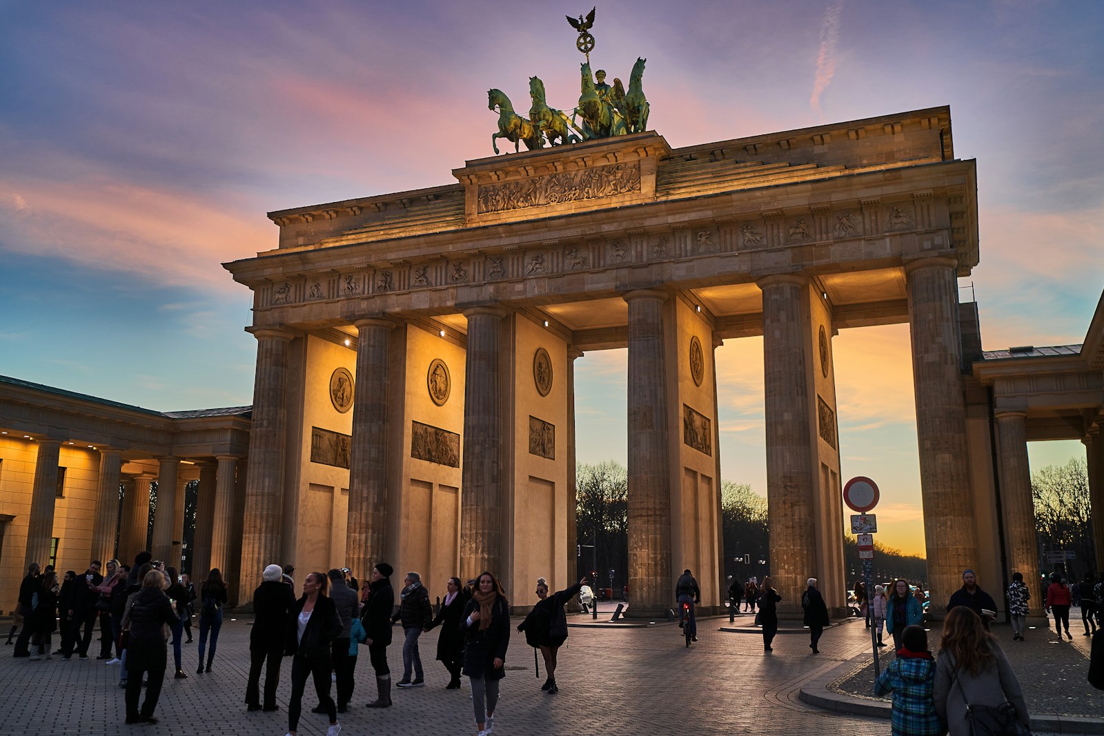 Brandenburg Gate illuminated at sunset with people gathered in front