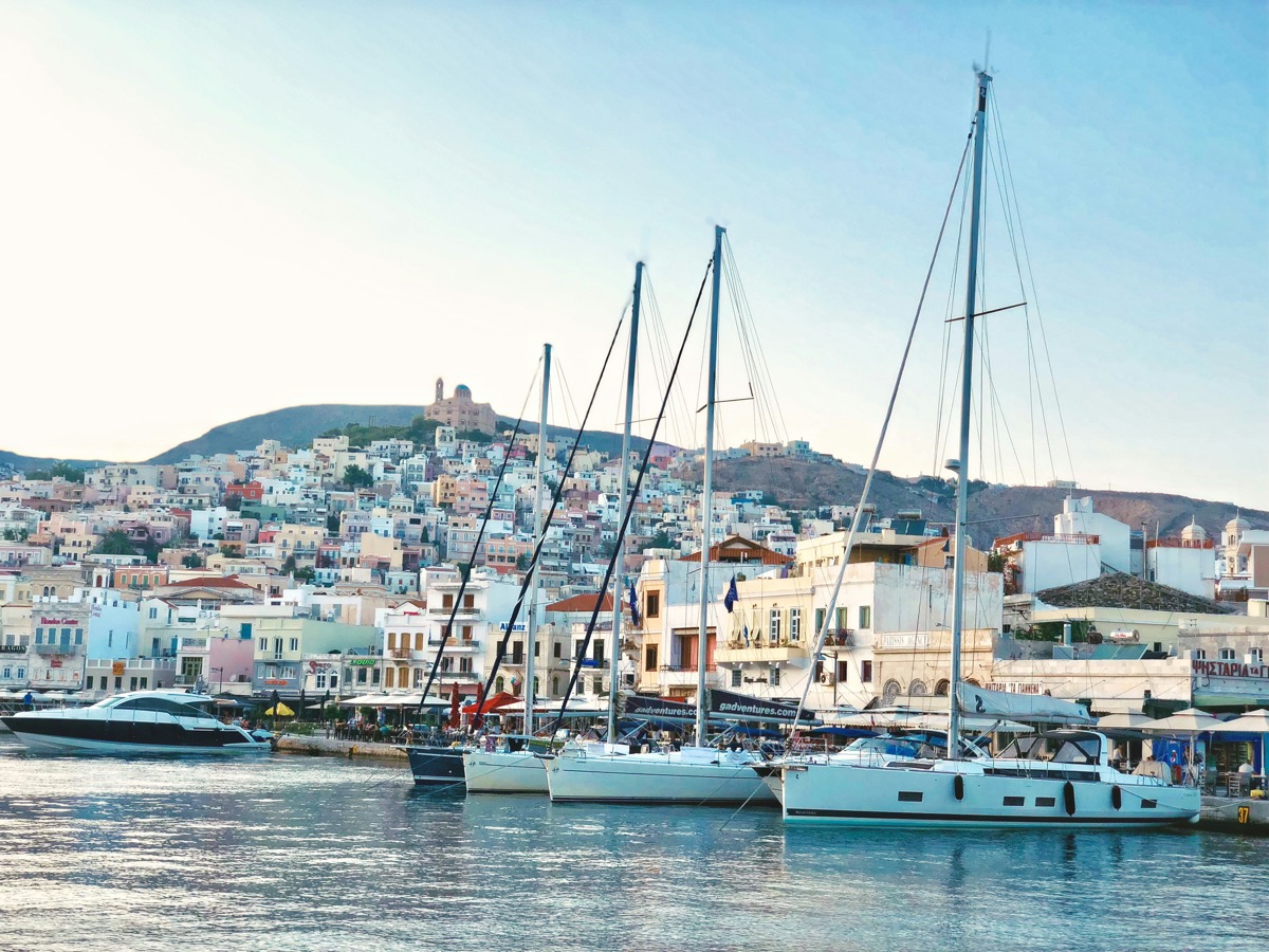 Sailboat on blue Aegean water representing island ferry travel in the Cyclades