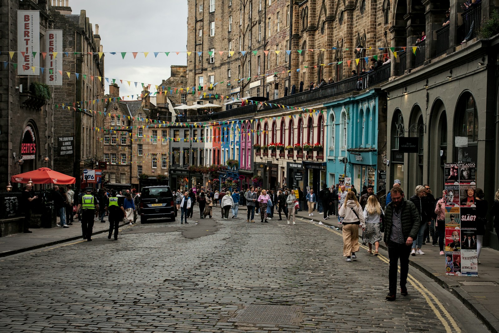 Colourful curved Victoria Street in Edinburgh's Old Town with tall buildings and shoppers