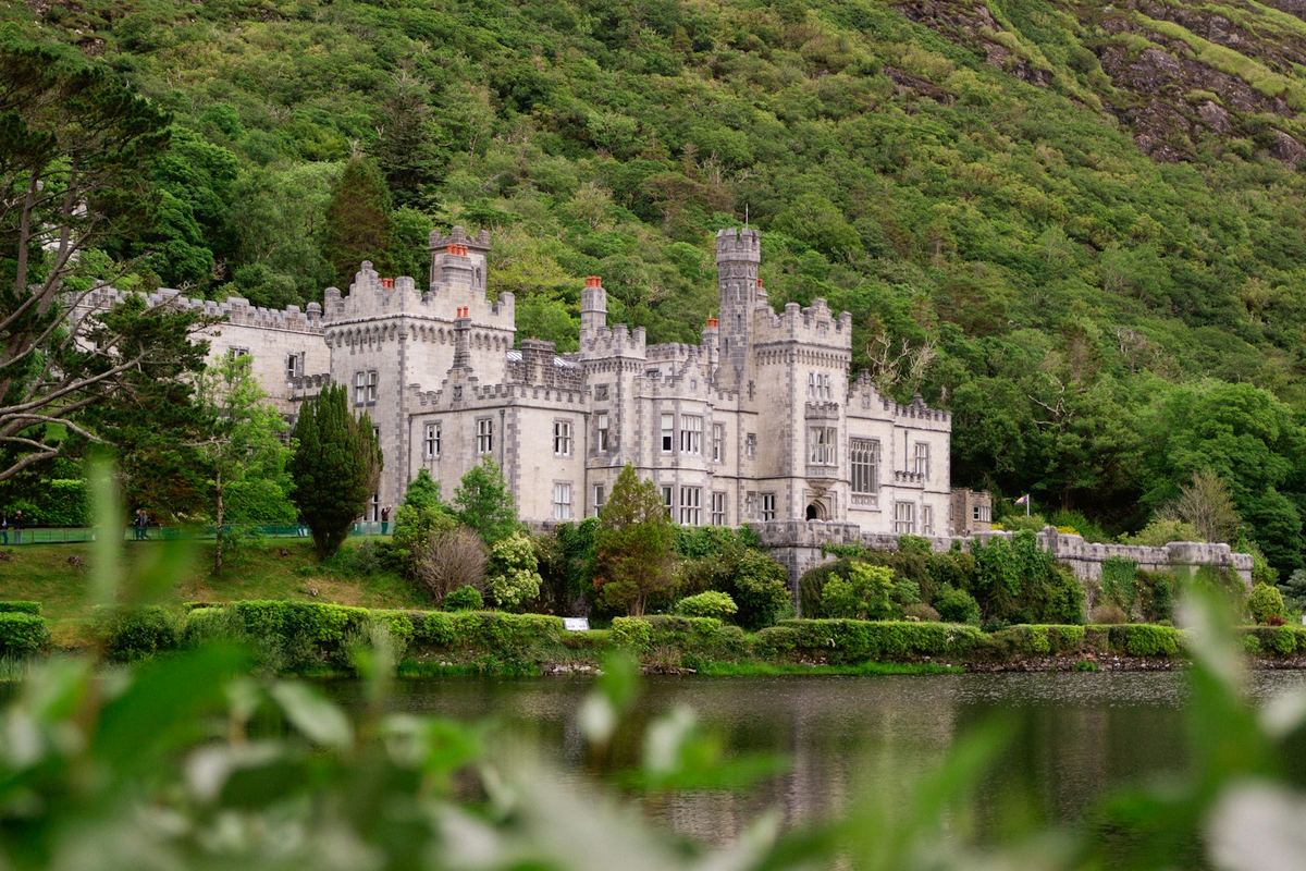Kylemore Abbey beside a lake, surrounded by woodland and mountains in Connemara