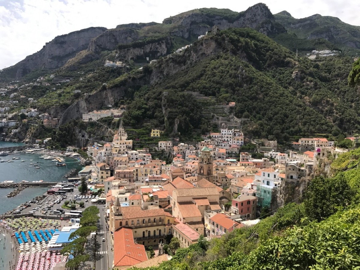 View over the town of Amalfi with terracotta rooftops, the harbour, and mountains rising behind