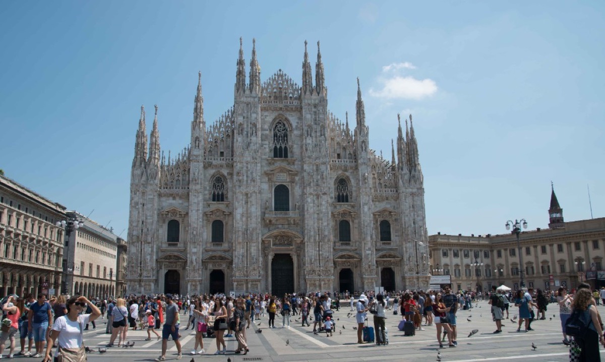 The Gothic facade of Milan's Duomo cathedral rising above a busy Piazza del Duomo
