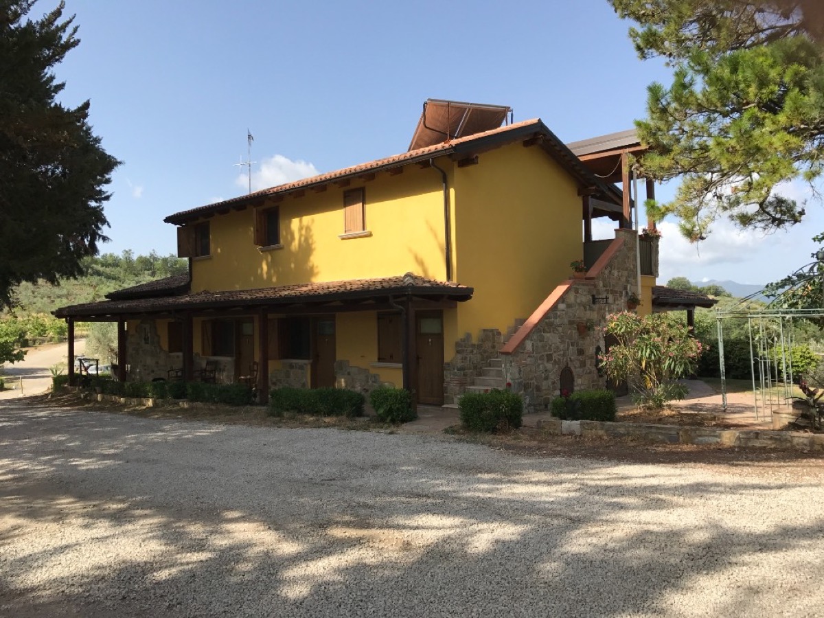 The yellow stone farmhouse of Villa Vea agriturismo surrounded by trees and hills in the Campania countryside