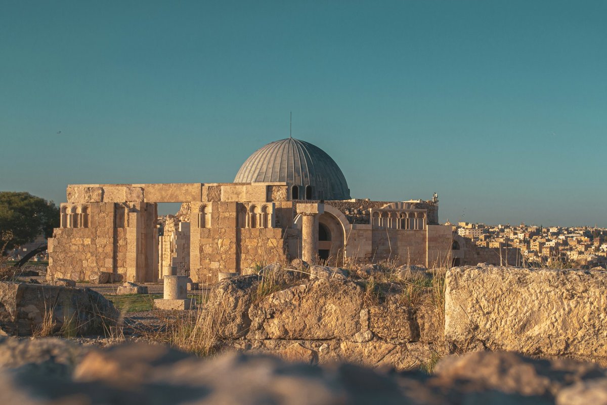Stone remains of the Amman Citadel under a blue sky, with the Temple of Hercules columns standing above the city