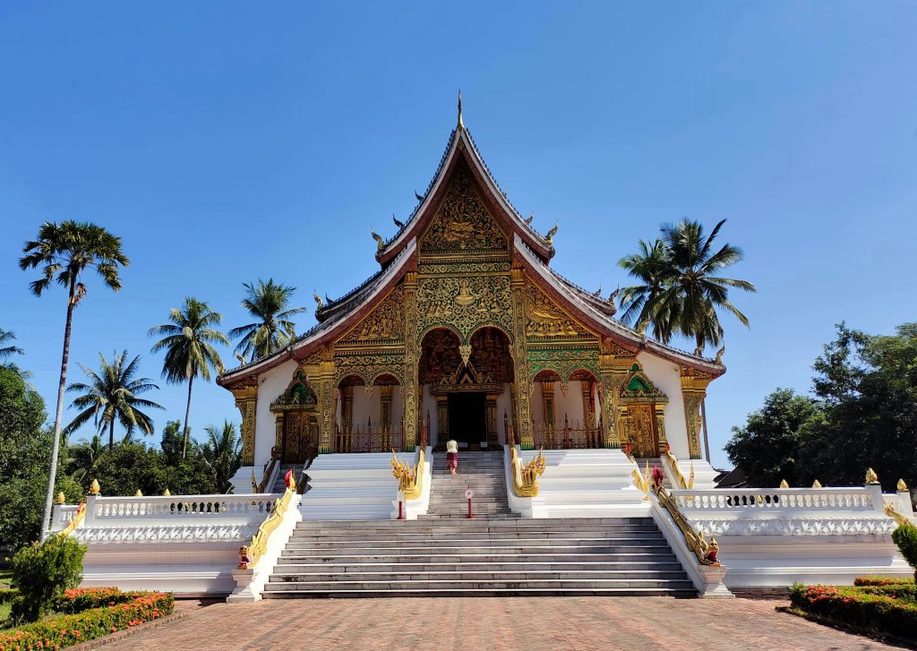 Ornate Lao temple facade and staircase under a clear blue sky in Luang Prabang