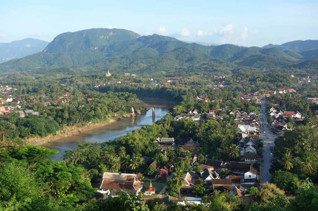 Elevated view of Luang Prabang with temple roofs, river and surrounding green mountains