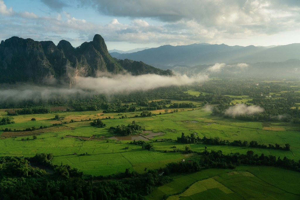 Aerial view of Vang Vieng limestone karsts rising above misty green rice paddies