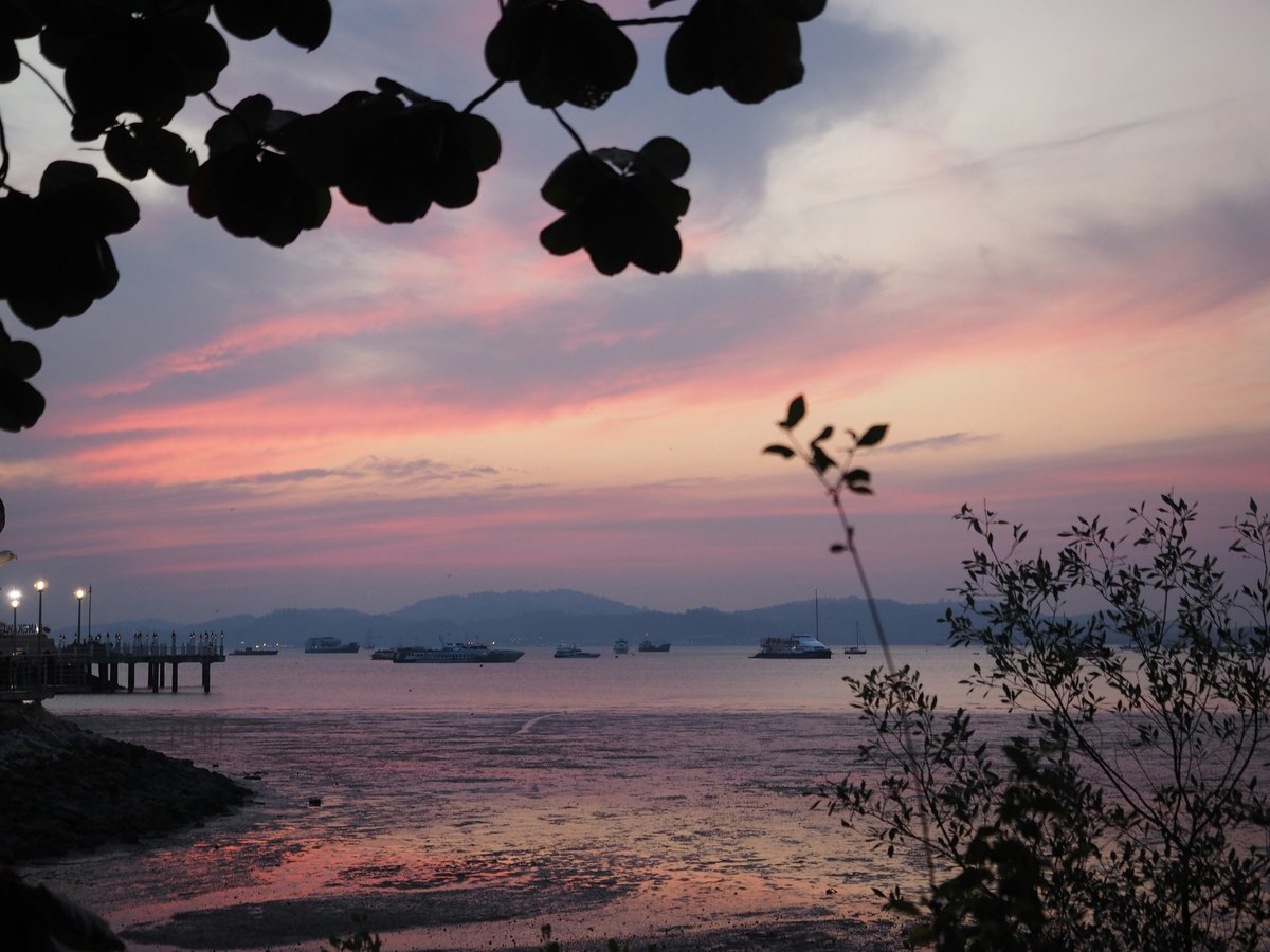Pink and orange sunset over calm water and distant islands in Langkawi