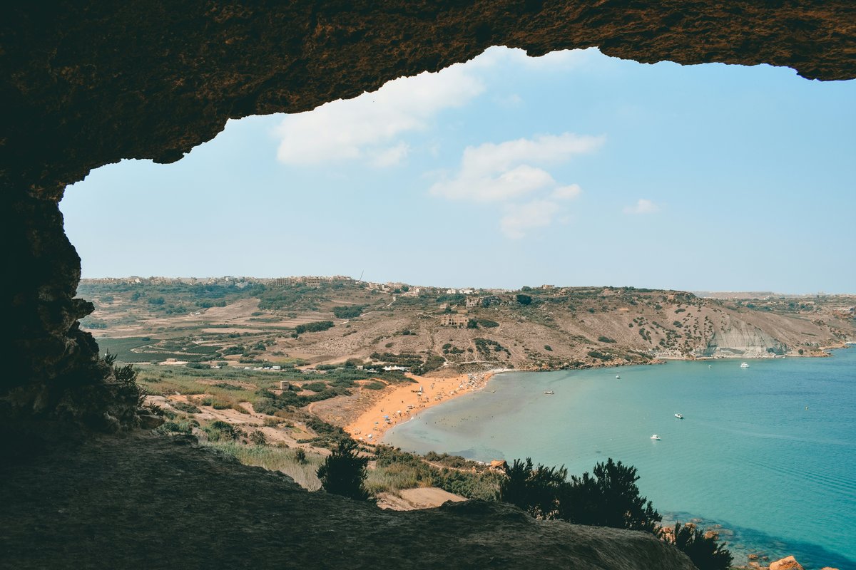 Ramla Bay's red-golden beach and turquoise water seen through the mouth of Tal-Mixta Cave on Gozo