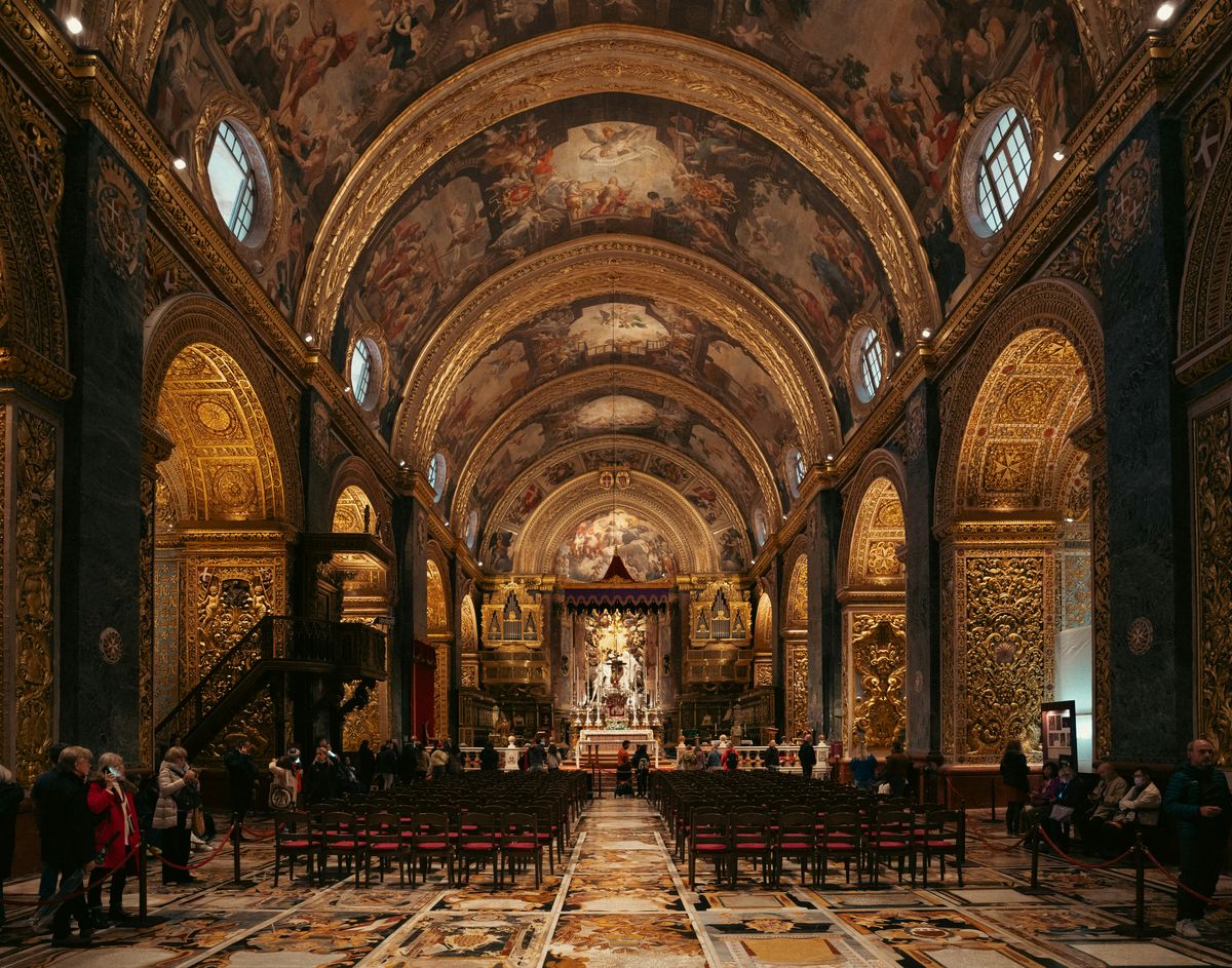 Interior of St. John's Co-Cathedral in Valletta with gilded walls, a marble floor and a painted vaulted ceiling