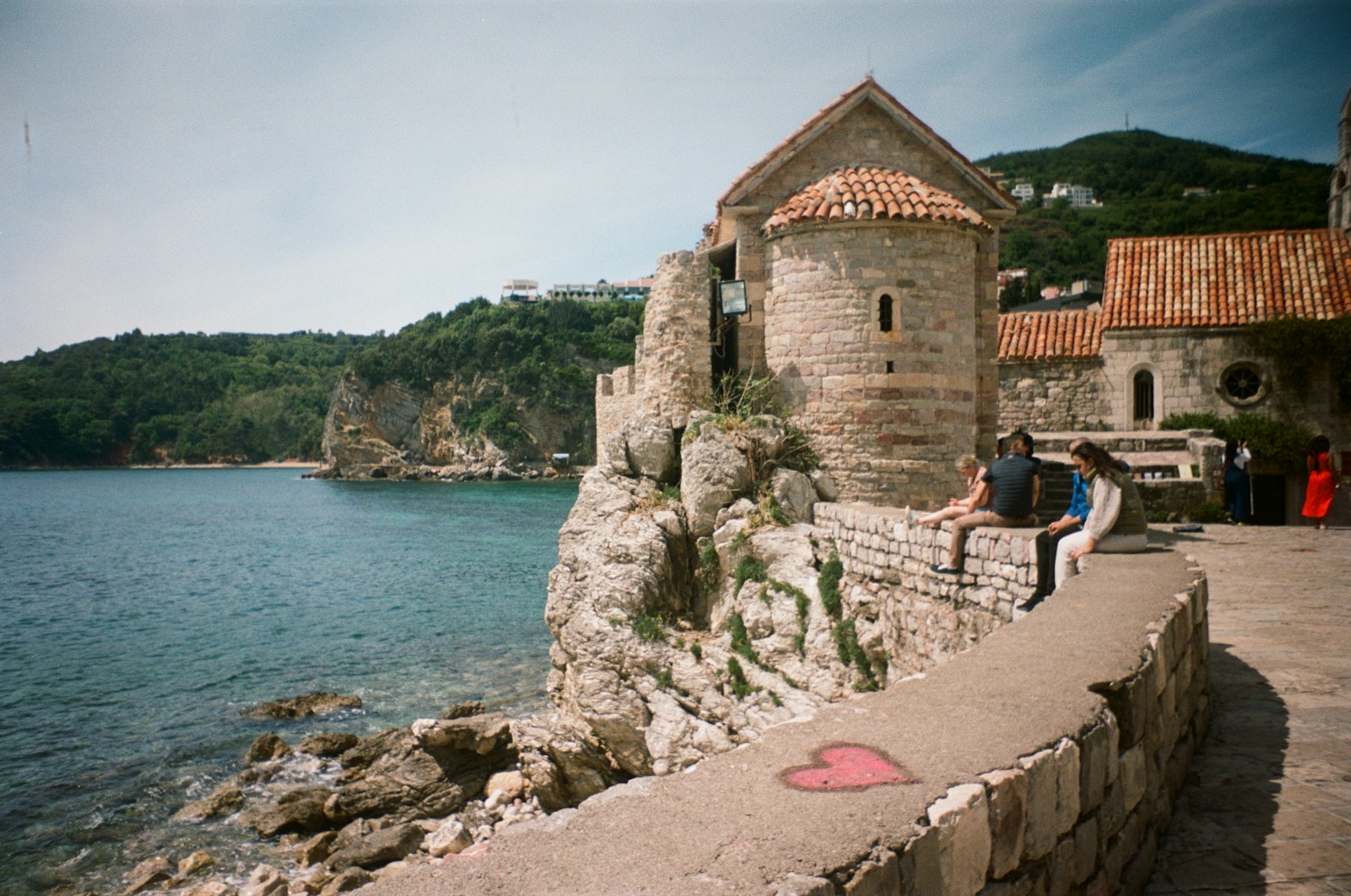 Historic stone church on the waterfront in Budva, on a cliff beside the blue sea