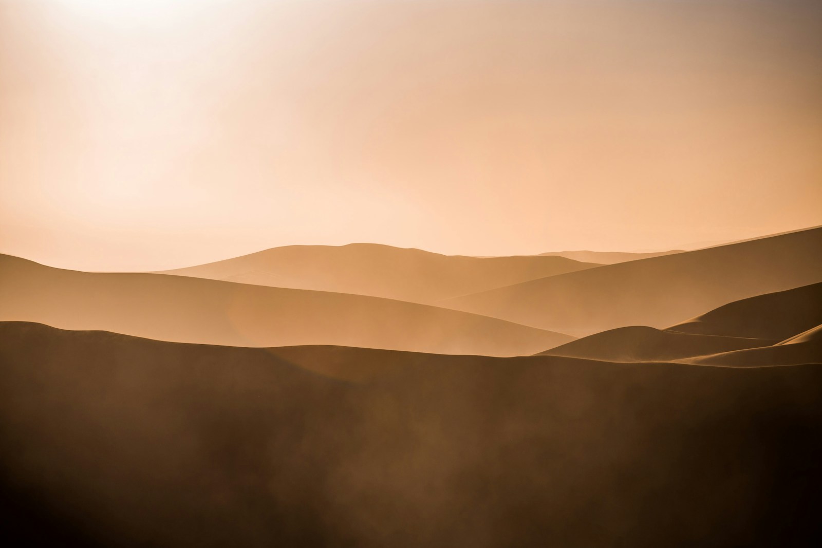 Hazy golden-hour view of rolling sand dunes at Sossusvlei, Namibia