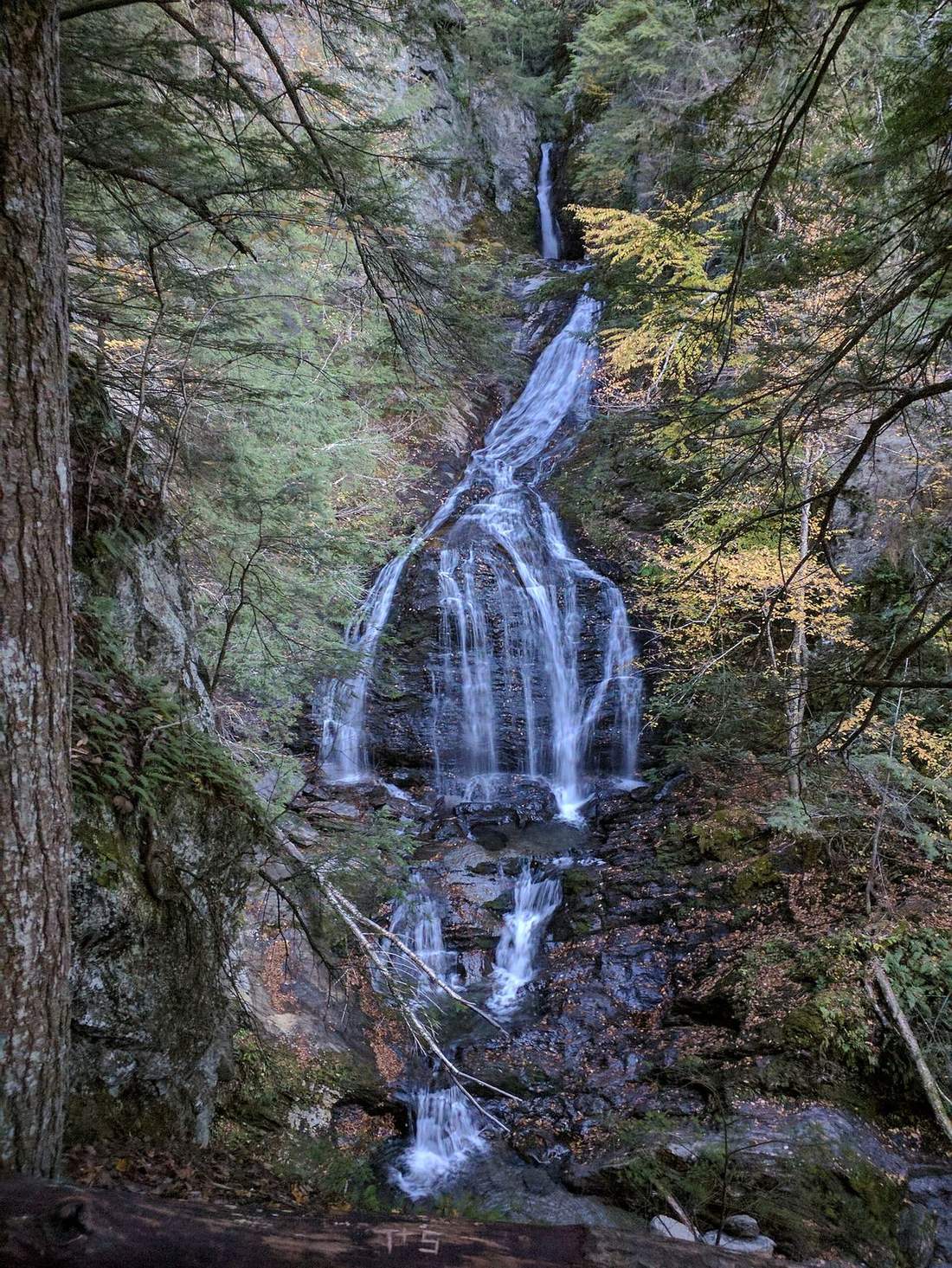 Moss Glen Falls surrounded by dense forest in Stowe, Vermont, photographed in autumn