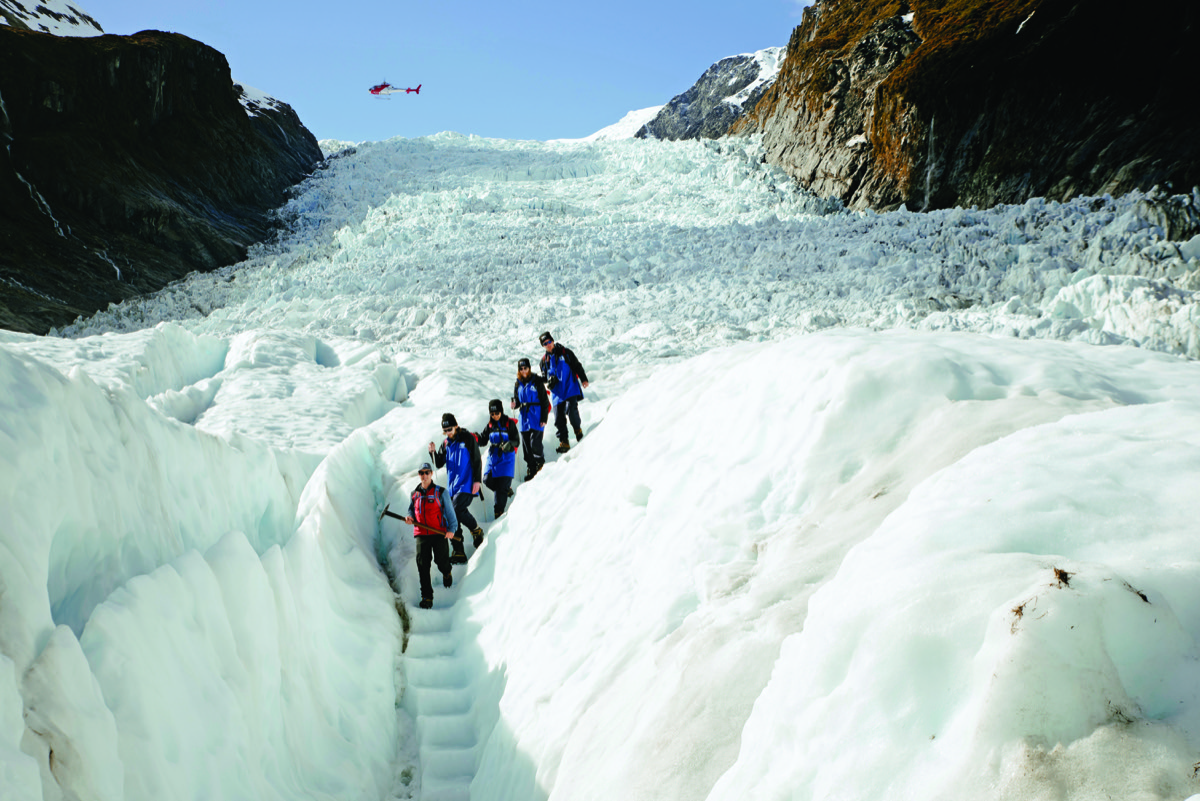 Helicopter landing on Fox Glacier with guided hiking group on the ice