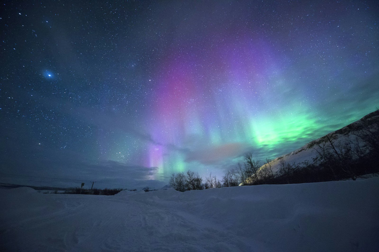 Northern lights over snow-capped mountains near Tromsø, Norway