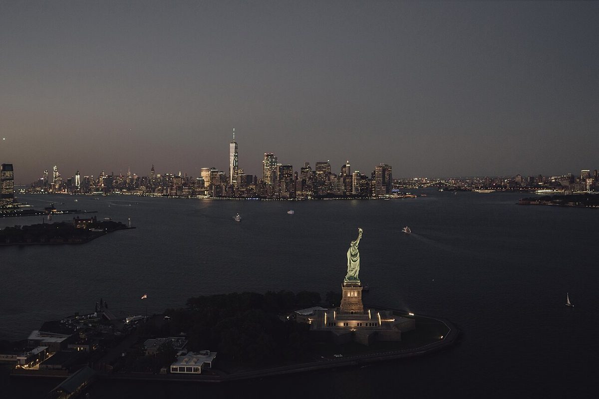 Aerial view of the Statue of Liberty with the New York City skyline at dusk