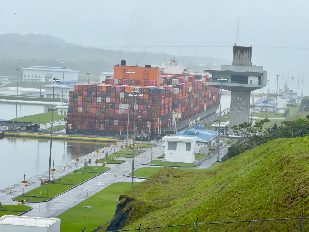 Container ship passing through Panama Canal locks near the Agua Clara control tower