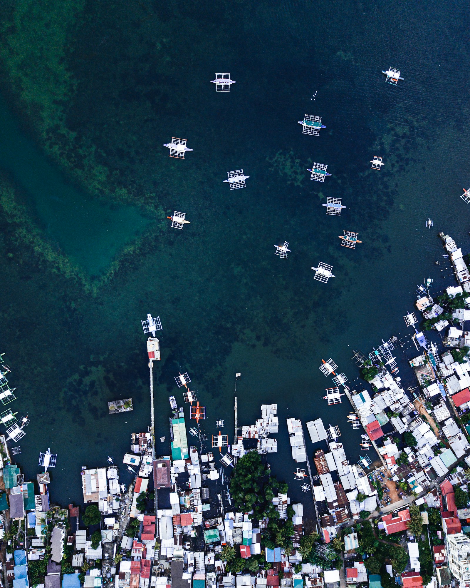 Aerial view of Coron Town shoreline with outrigger boats and turquoise coastal waters