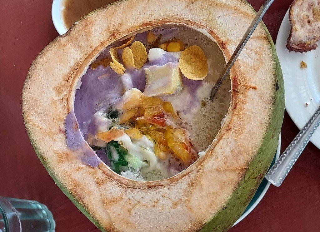Halo-halo Filipino dessert served in a hollowed green coconut with ube, leche flan and toppings