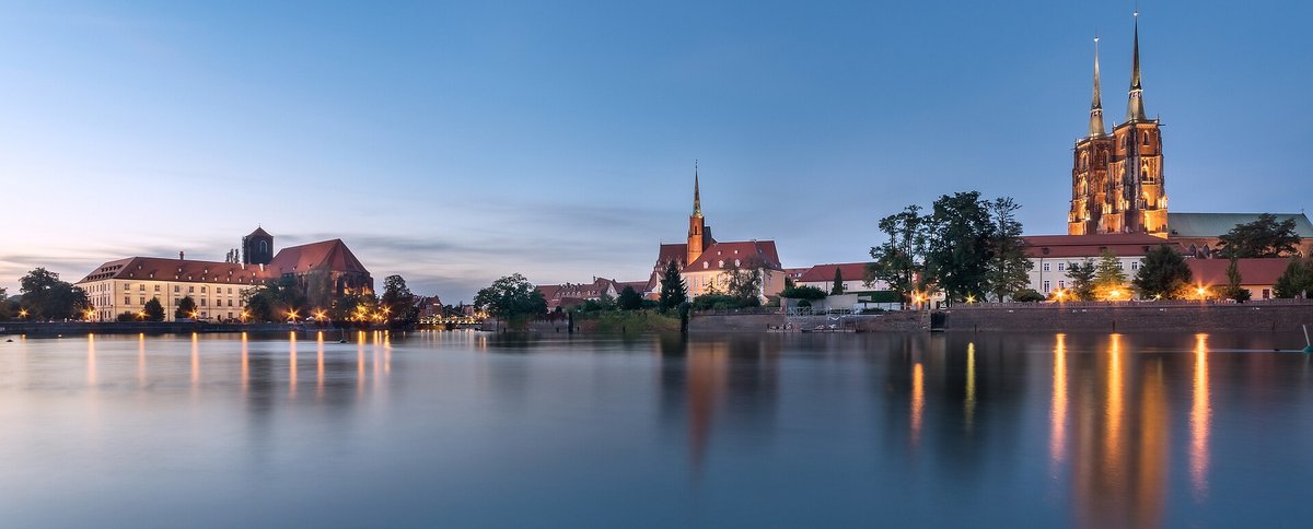 Evening panorama of Ostrów Tumski in Wrocław, with the twin spires of the cathedral reflected in the Oder River