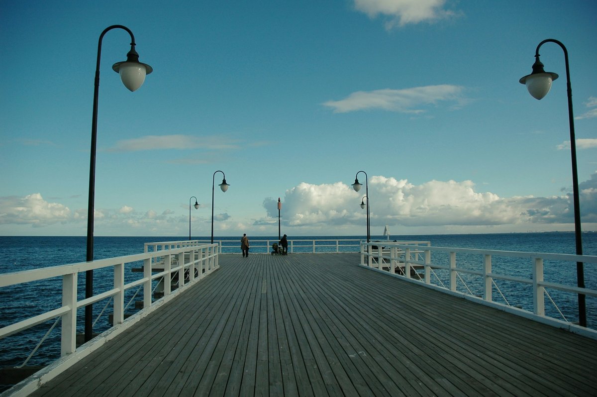 A wooden pier with white railings and street lamps stretching out over the Baltic Sea at Sopot