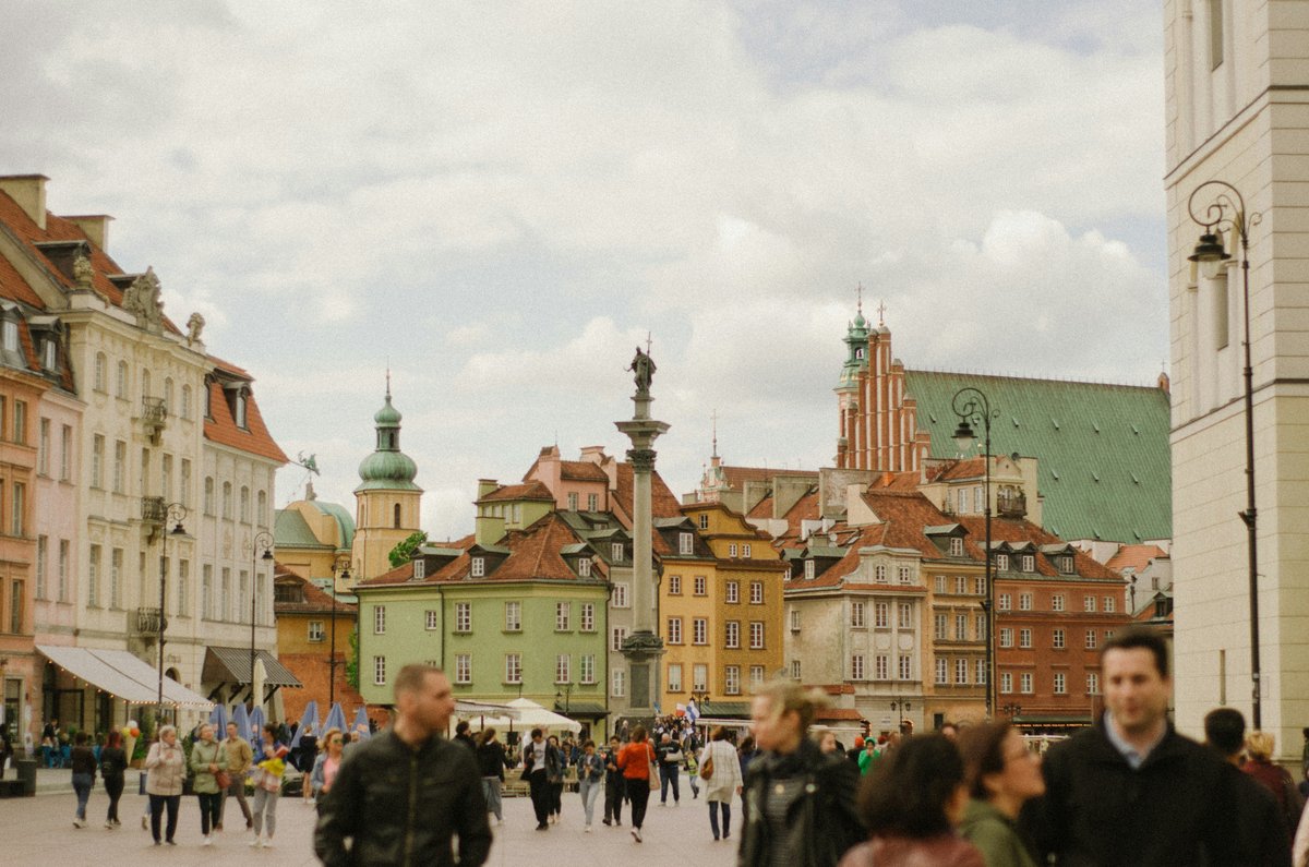 Sigismund's Column rising above Castle Square in Warsaw's Old Town, with colourful historic houses and people walking