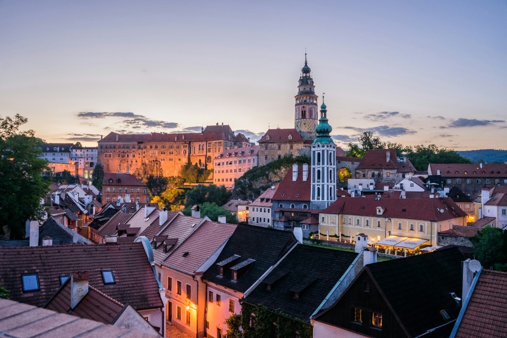 Český Krumlov at dusk with illuminated castle tower and red rooftops of the old town