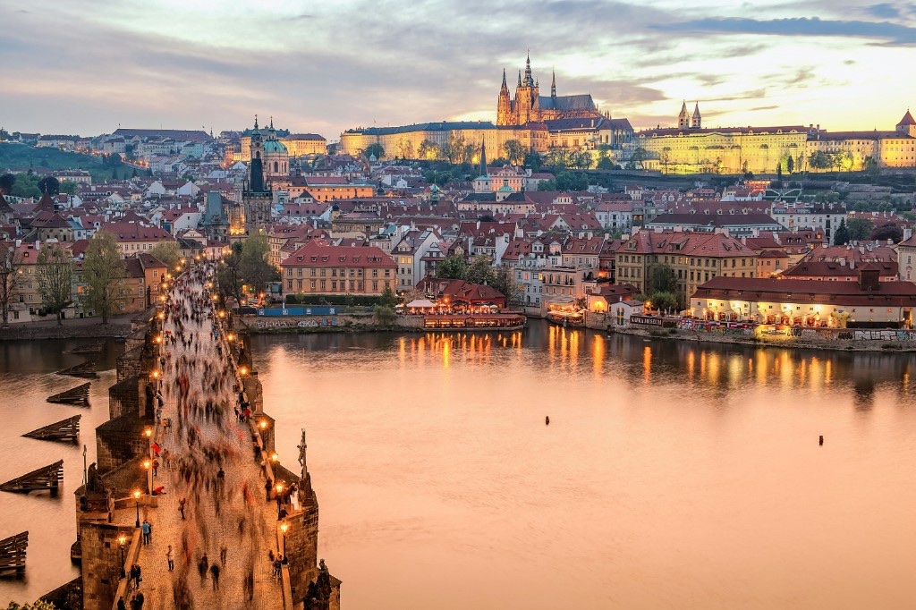 Charles Bridge at twilight with Prague Castle and St. Vitus Cathedral illuminated above the Vltava