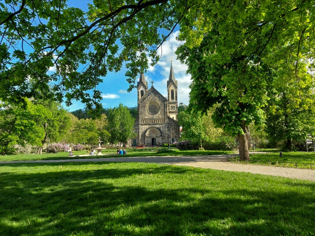 Church of Saints Cyril and Methodius framed by park trees in Karlín, Prague