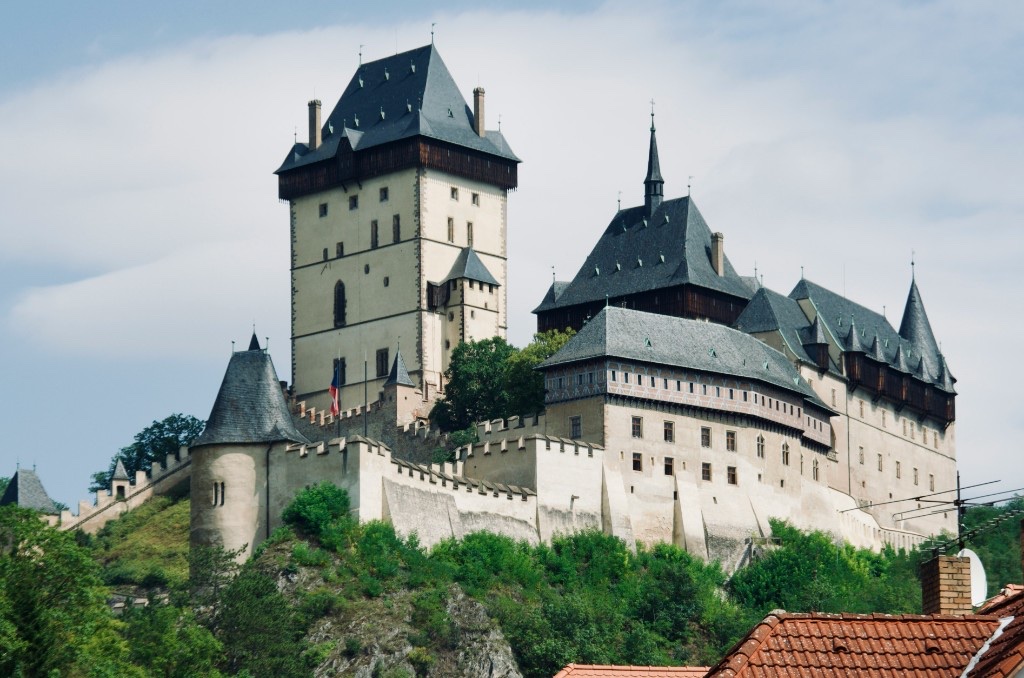 Karlštejn Castle rising above forested hills with the village rooftops below
