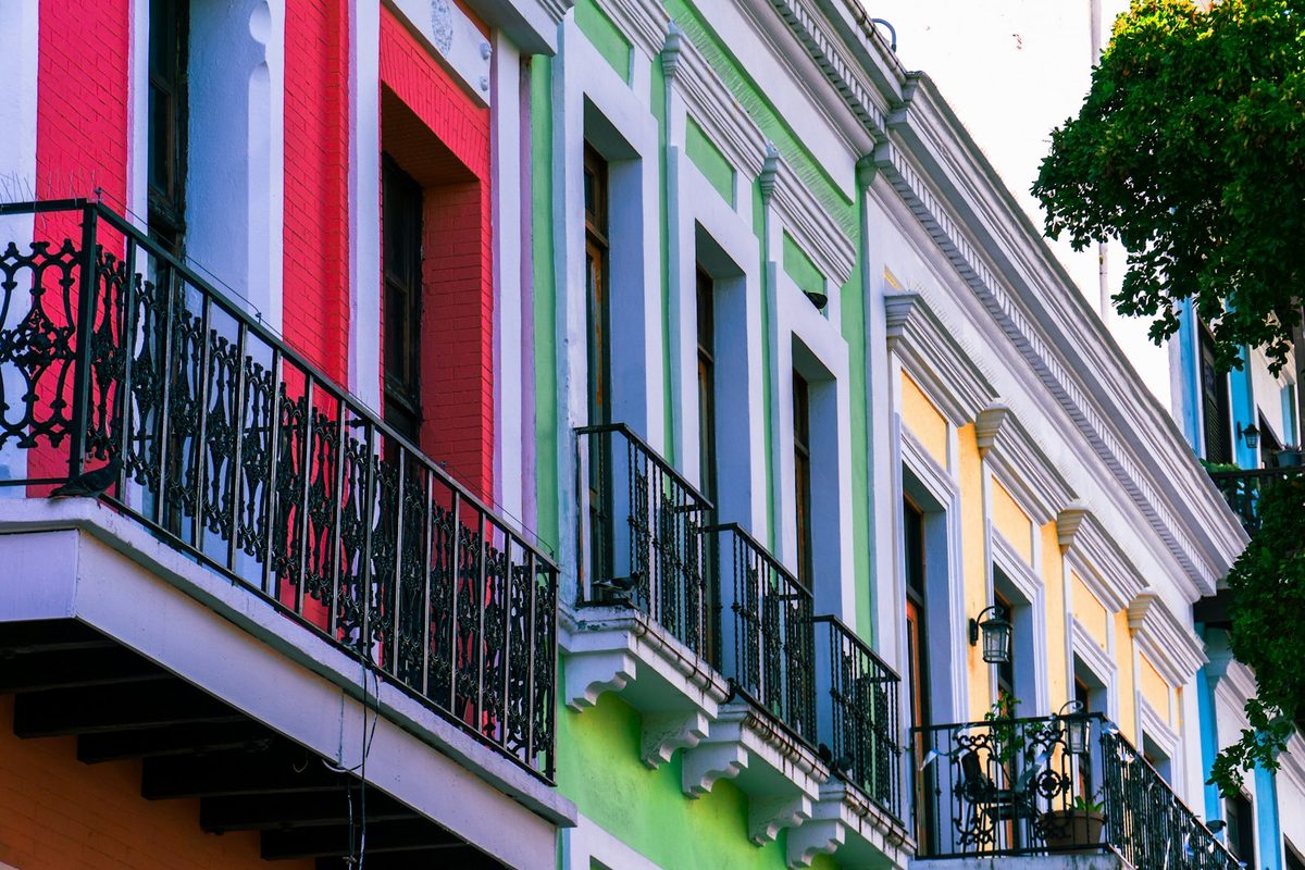 Bunte Häuser mit Balkonen und Fenstern entlang einer lebendigen Straße in Alt-San Juan, Puerto Rico