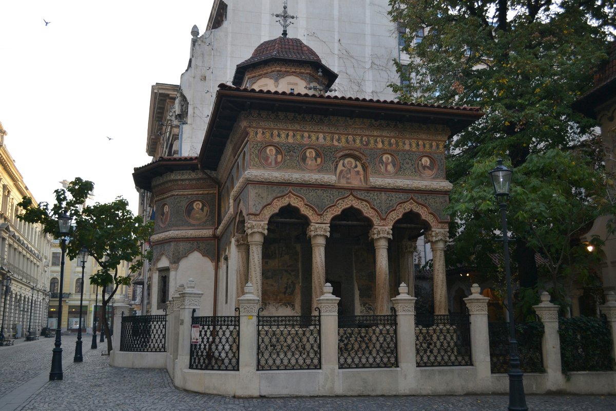 Stavropoleos Monastery Church in Bucharest, with its carved stone arcade, painted details and small dome behind an ornate fence